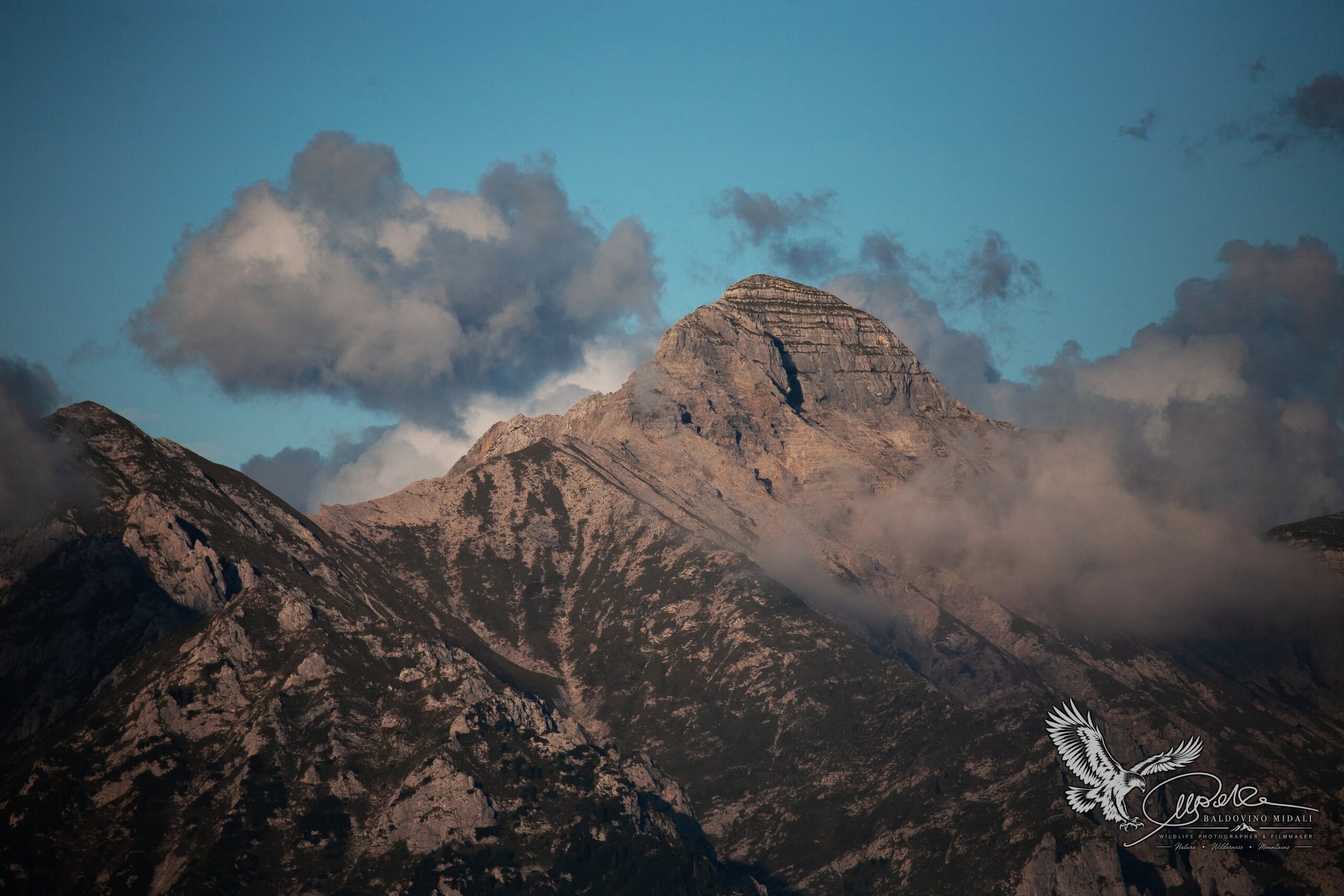 Cima montuosa che emerge tra le nuvole in un paesaggio d'alta quota